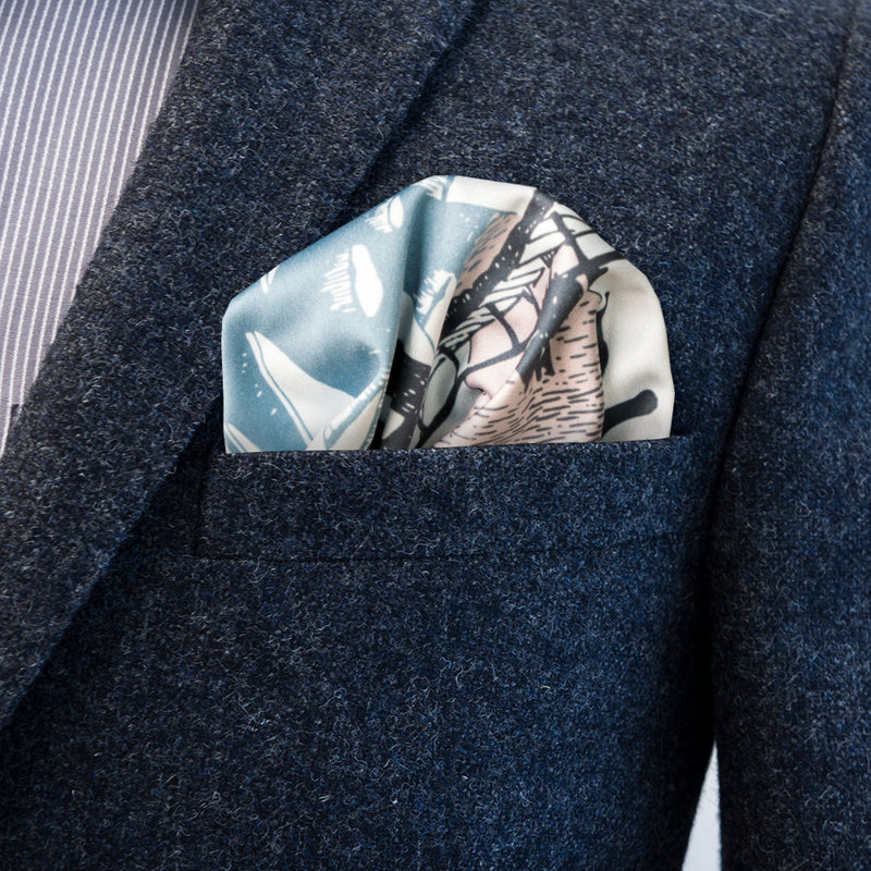 Blue, bluegray, and pale pink Moomin Bridge multipurpose pocket square by FatCloth puff fold in gray blazer pocket.